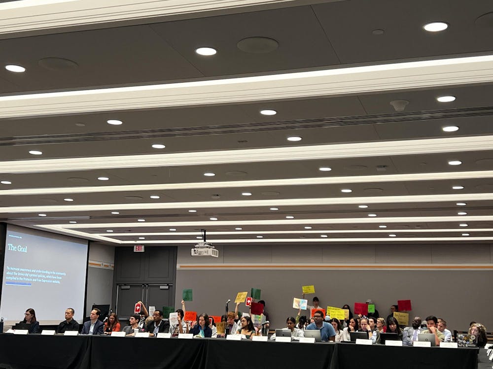 A group of people hold signs behind people sitting down at a meeting.