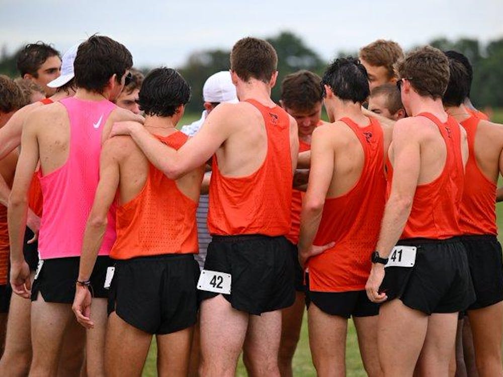 group of guys in orange and black uniforms huddle before starting the run