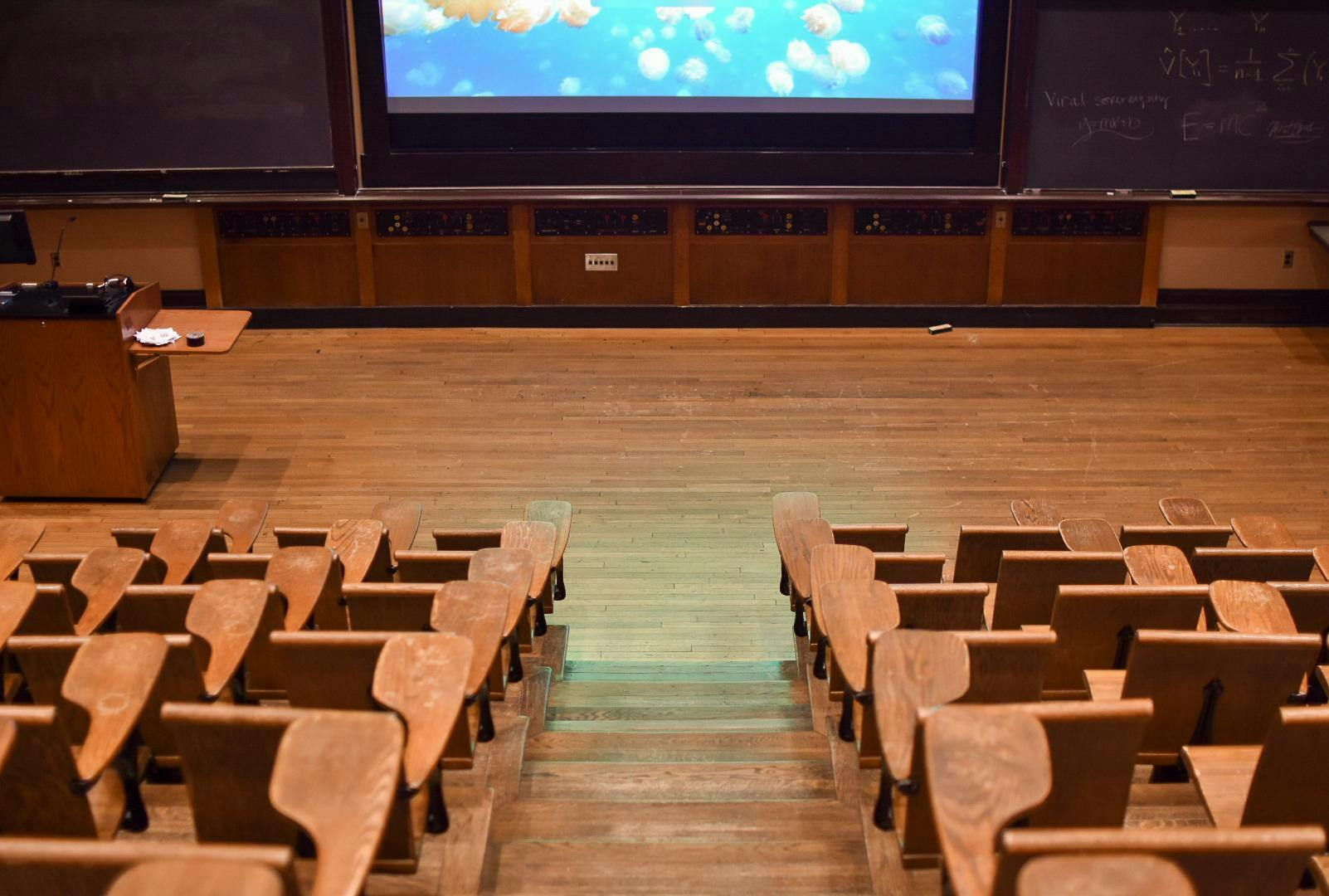 A bird’s eye view photo from behind the seats of an empty classroom.