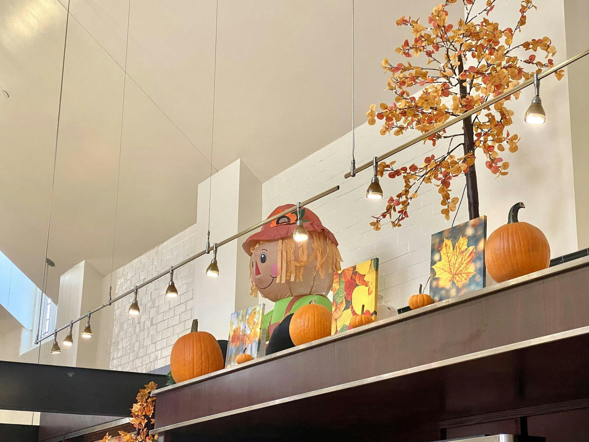 An inflatable scarecrow figure and fall foliage leaves are places on the ledges of the dining hall ceiling. 