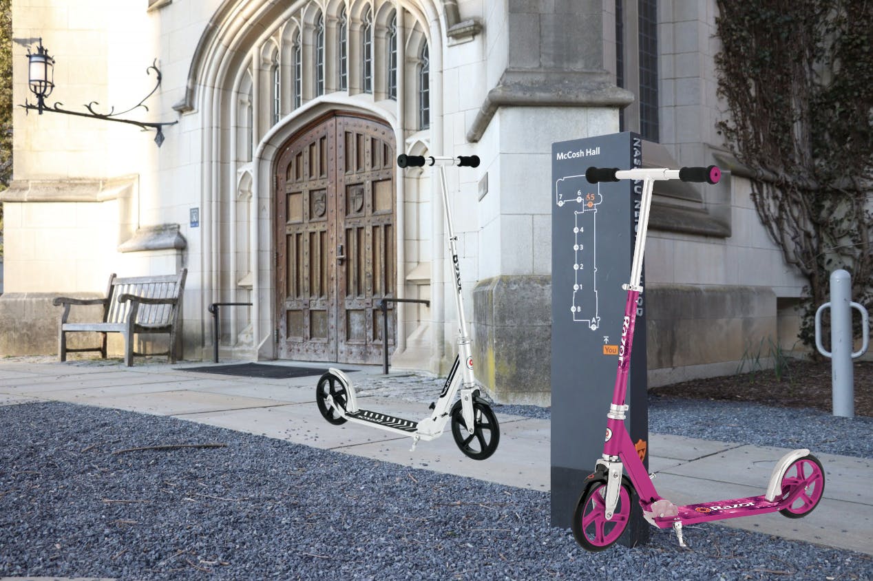 A stone academic building with a big door with two scooters photoshopped in front.