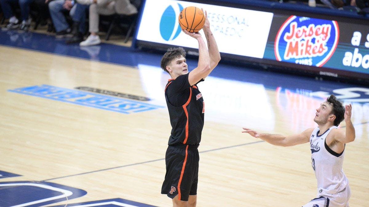 Man in black and orange jersey shoots a basketball