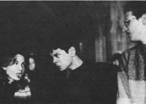 A black and white image of Dale E. Ho staring at a woman who is sticking her tongue out at him. Another man is stood on the right of Ho.