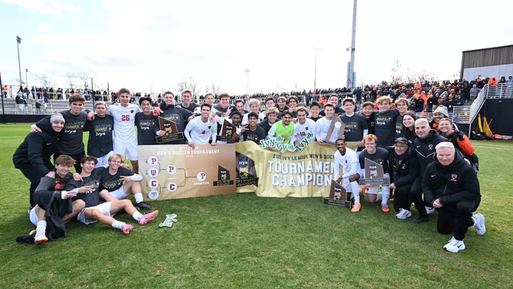 Big team and coaches celebrating win on soccer field, posing for photo.