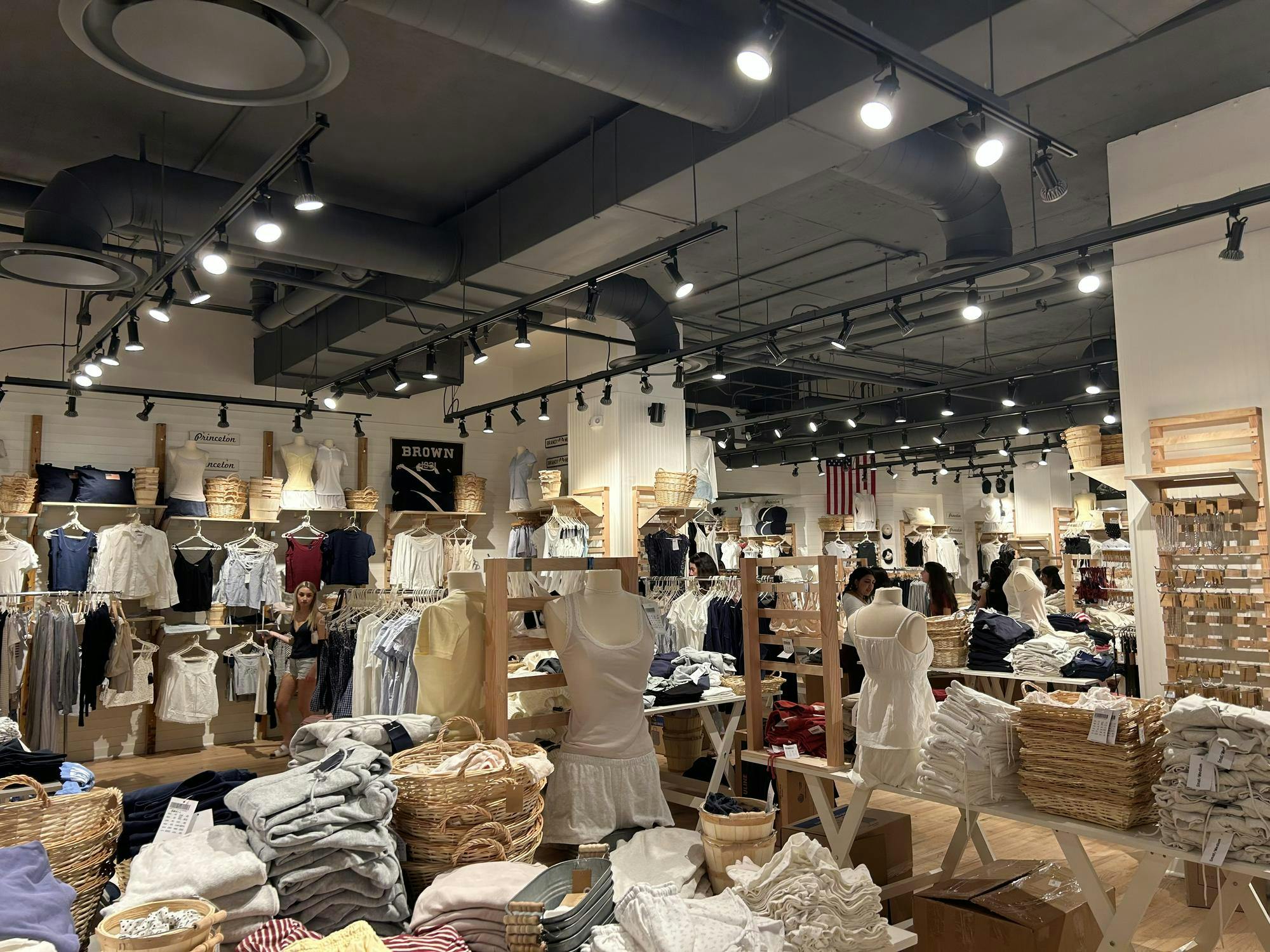 Inside of a store lit up by bright lights. Pastel clothing are displayed throughout the store.