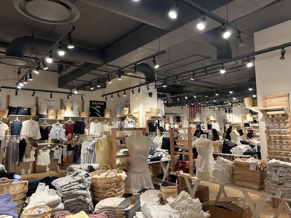 Inside of a store lit up by bright lights. Pastel clothing are displayed throughout the store.