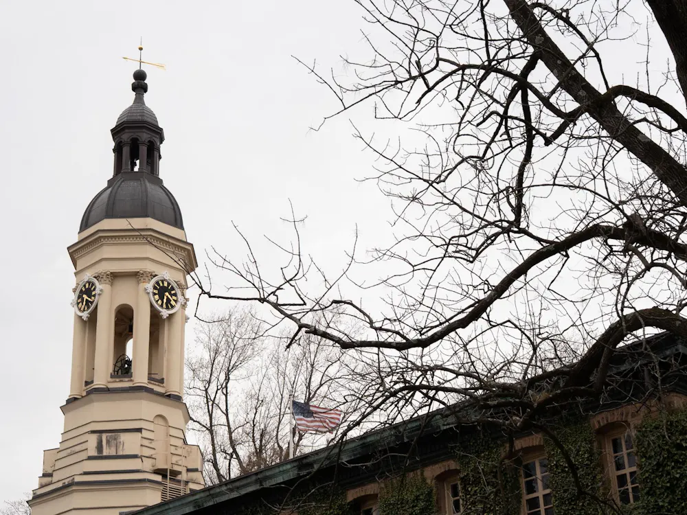 A building with a bell tower on the left side and an extension on the right. A tree with no leaves is in the foreground.