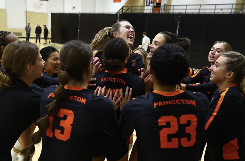 Volleyball players smile and celebrate in huddle.