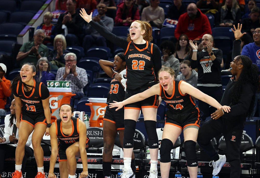 Five women's basketball members celebrating in front of a crowd.