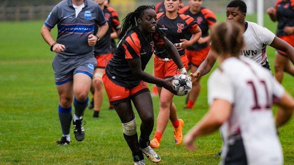 A rugby player prepares to toss ball to her teammate