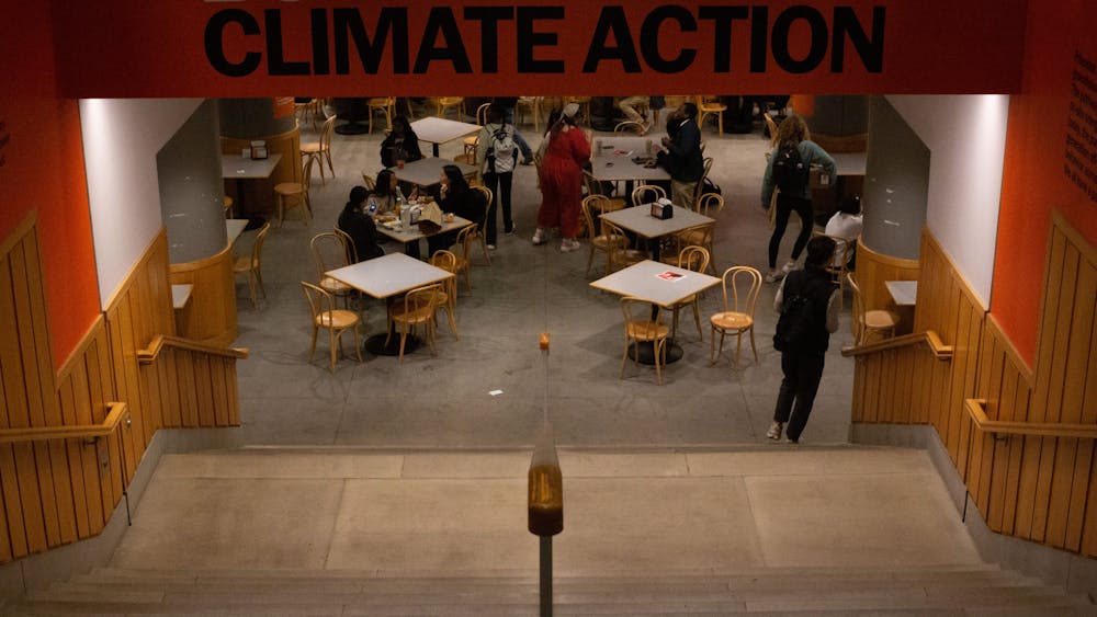 Concrete staircase leading into dining area with people seated at square wooden tables. Banner above the stairway reads "Builds climate action"