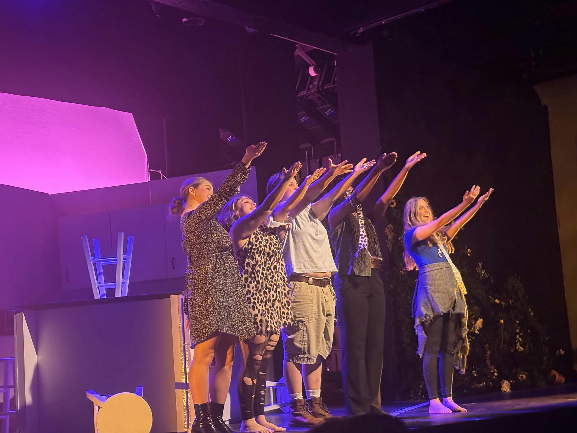 Five actors gesture out beyond the stage to the audience.