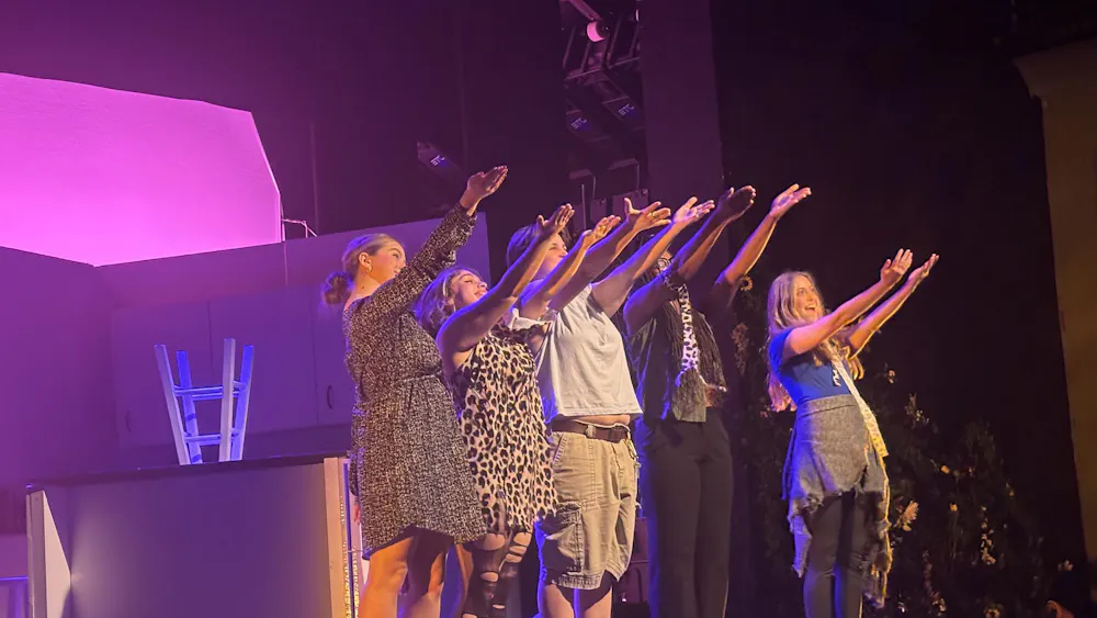 Five actors gesture out beyond the stage to the audience.
