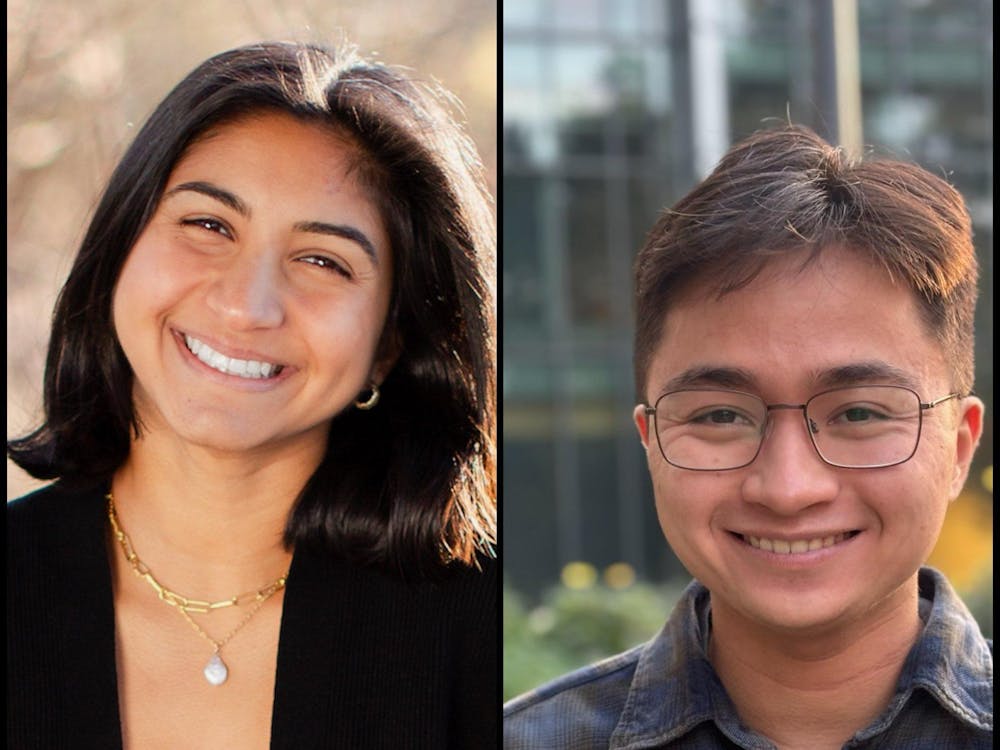 A woman with a short bob and a man with glasses smile at the camera.
