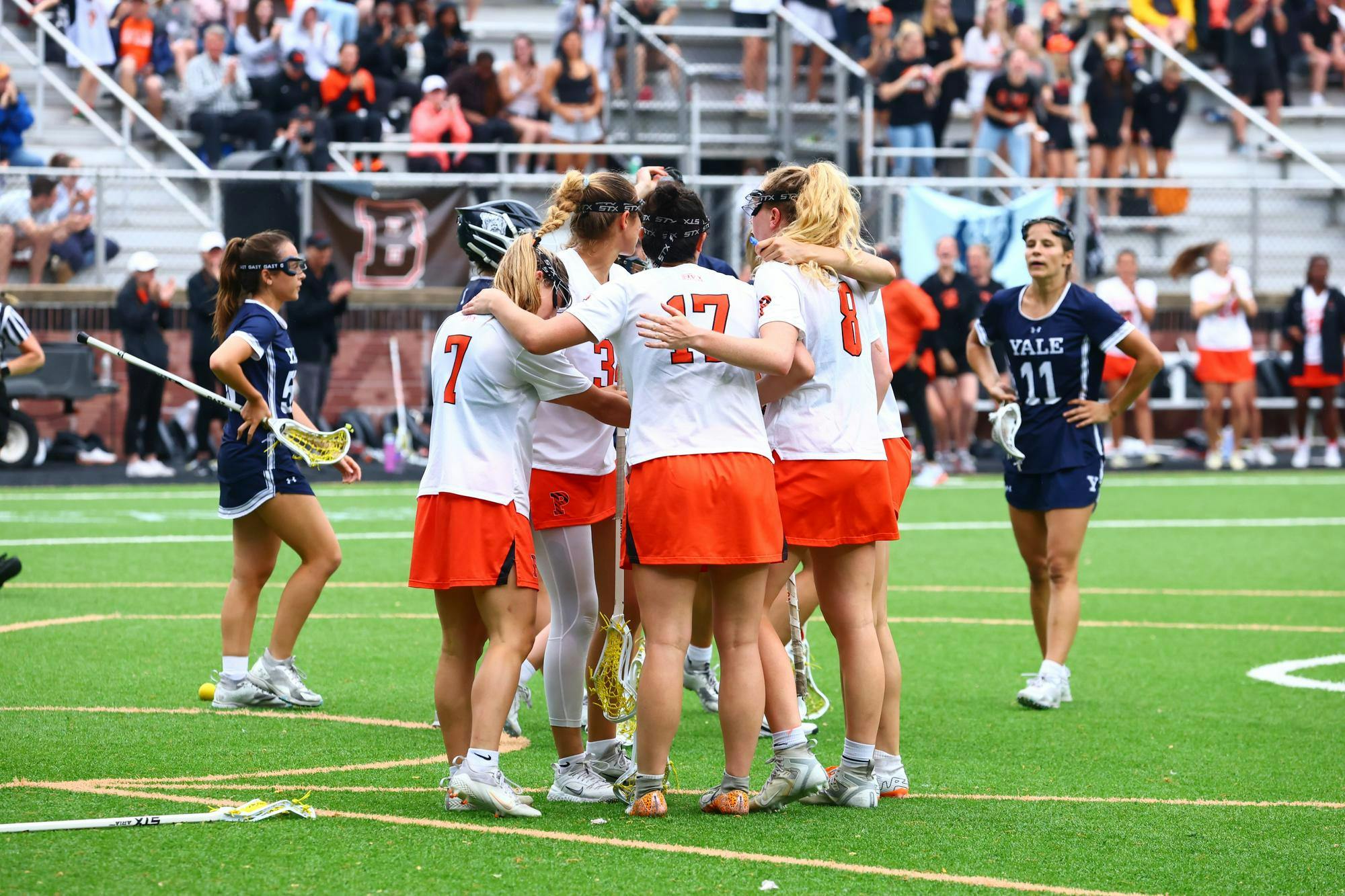 Women’s lacrosse team huddles on field.