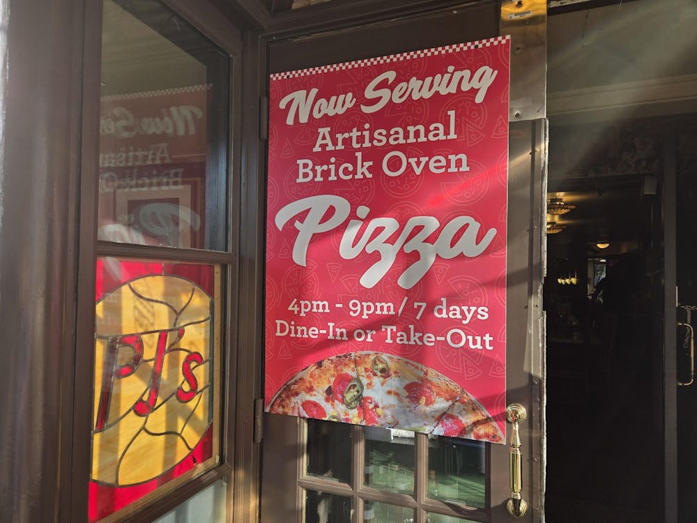 Red sign on door with white text advertising pizza sold from4 p.m. to 9 p.m. daily. 