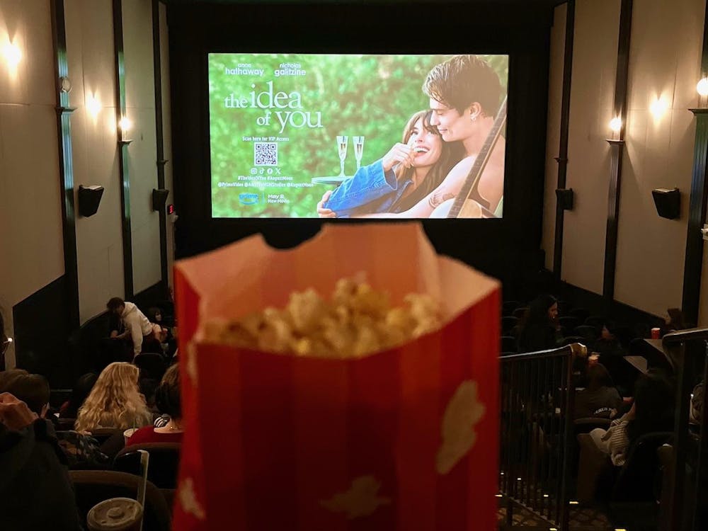 A bag of popcorn before a movie theatre screen.
