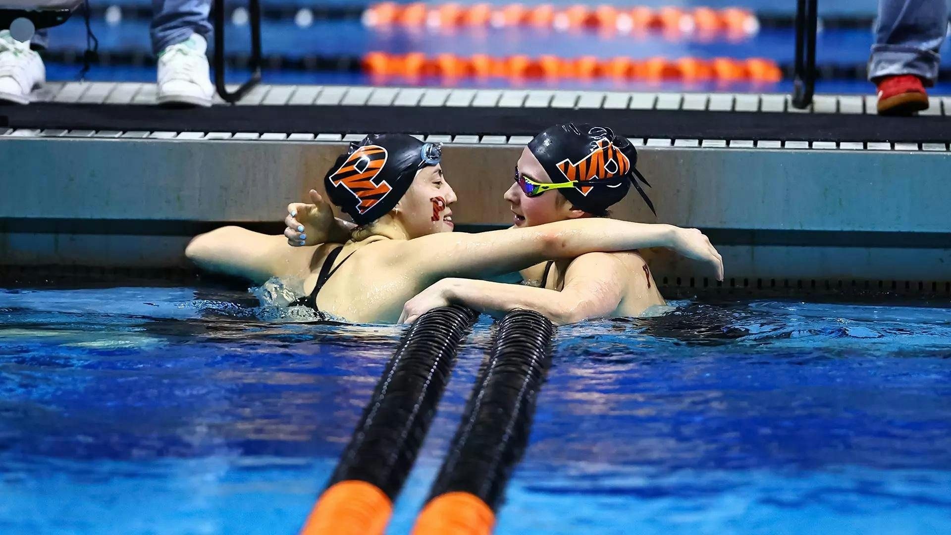 Two Princeton swimmers hug each other despite being separated by two orange and black lane lines.