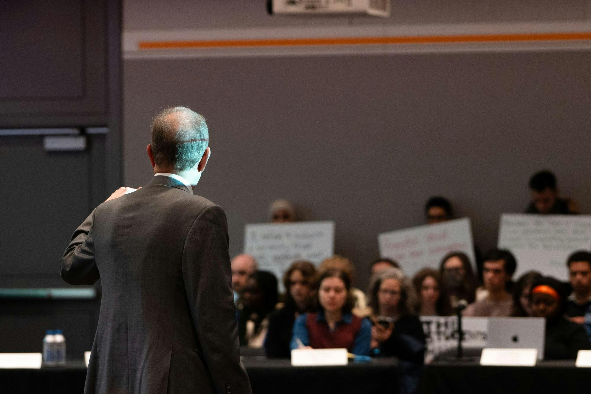 a man gestures towards a crowd holding signs 