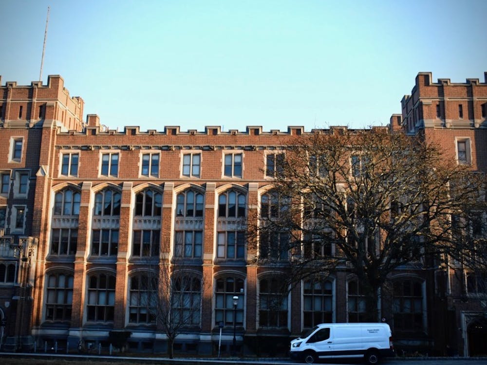 A large brick building with many arched windows stands against a blue sky.