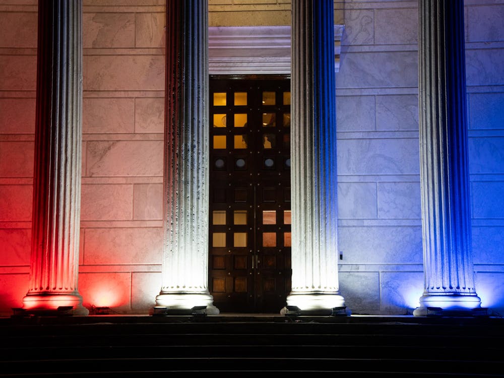 A white marble building with white columns in front, lit up with red and blue lights