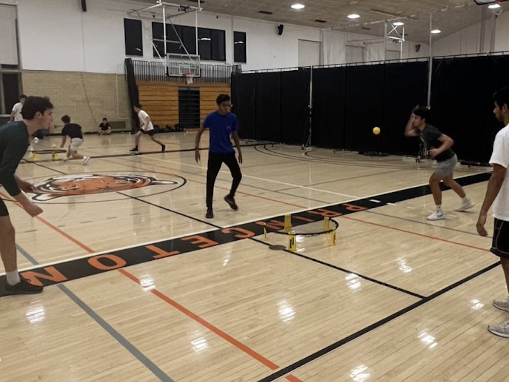 Four men on a court slapping a ball on a circular net