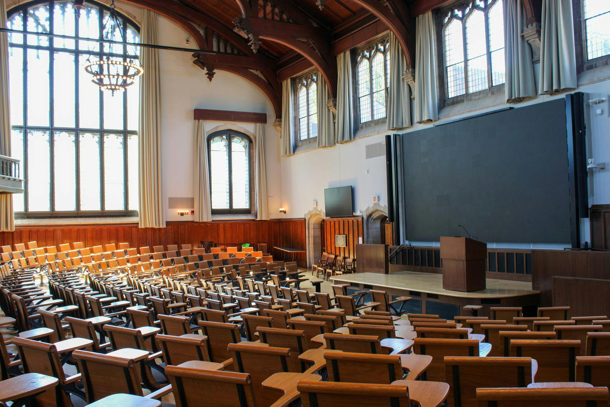 An empty room with wooden desks and a large window.