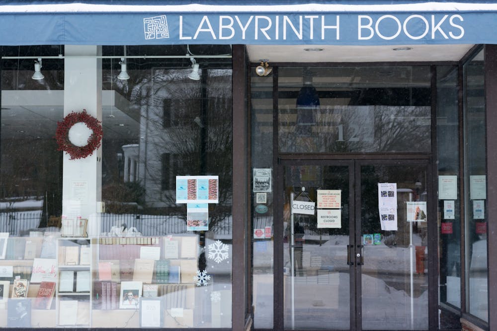 A storefront with a blue awning and multicolored books behind a glass window.