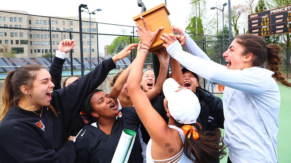 Women in black jackets raise brown trophy