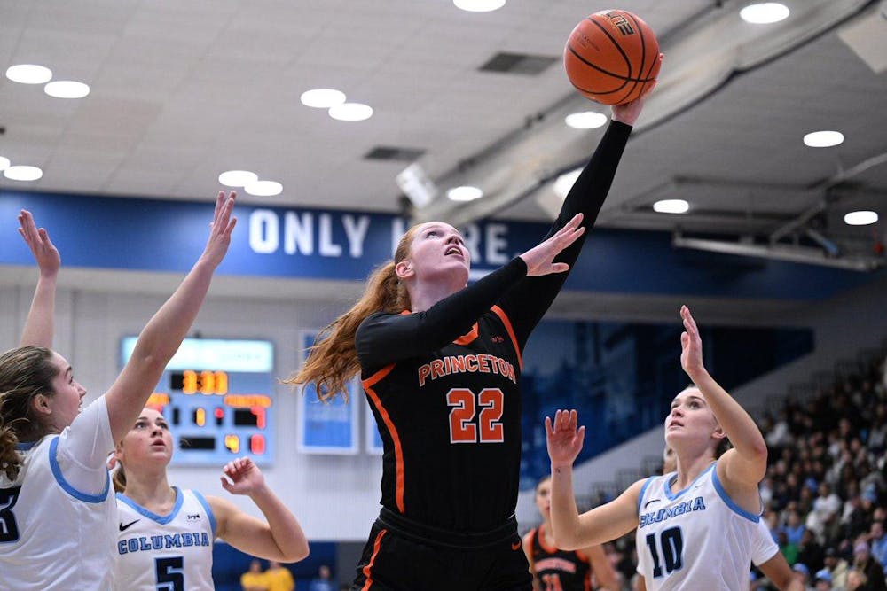 Parker Hill in black jersey with orange details rises for a layup, surrounded by Columbia players in white and blue.