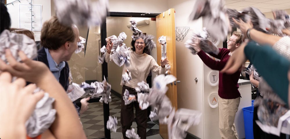 A girl with short hair and glasses is pelted with newspaper balls by a group of students.