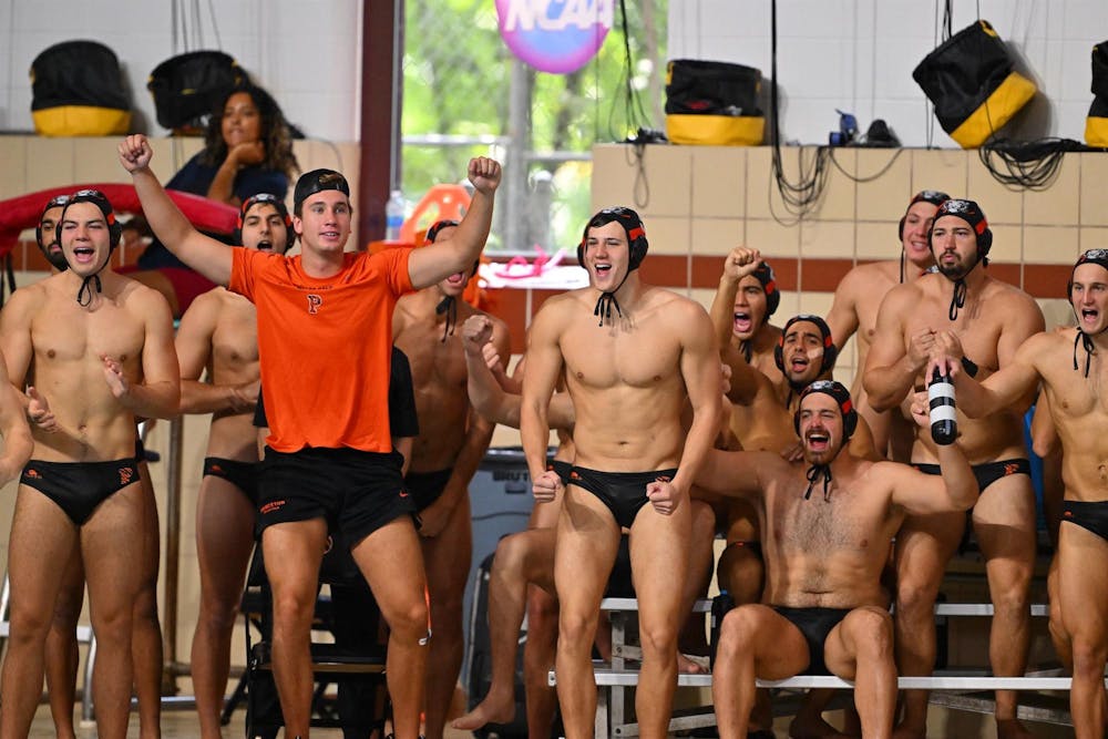Man in orange t shirt and water polo team in black speedos. 