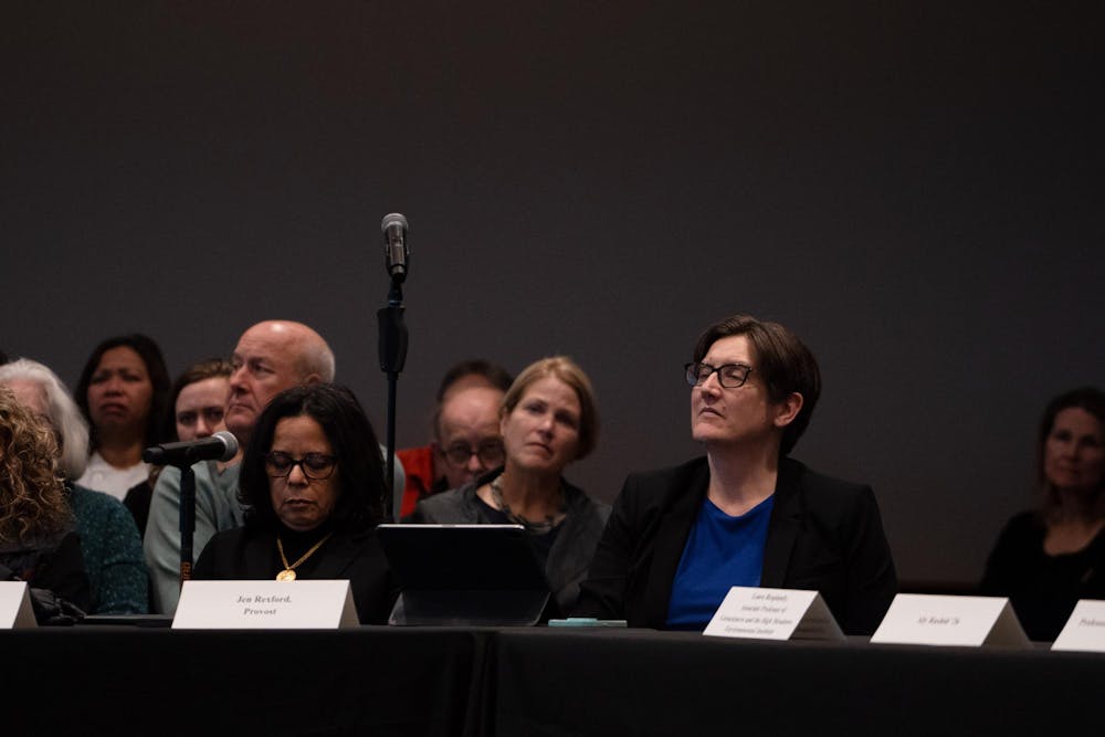 A woman sitting at a table with a placard in front of her at a meeting.