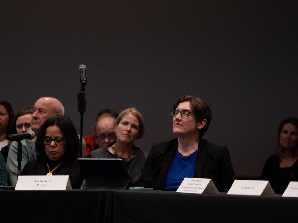 A woman sitting at a table with a placard in front of her at a meeting.