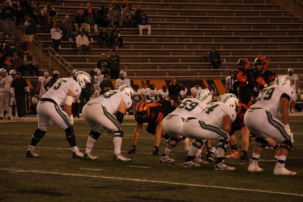 Football teams lining up against each other at night in stadium.