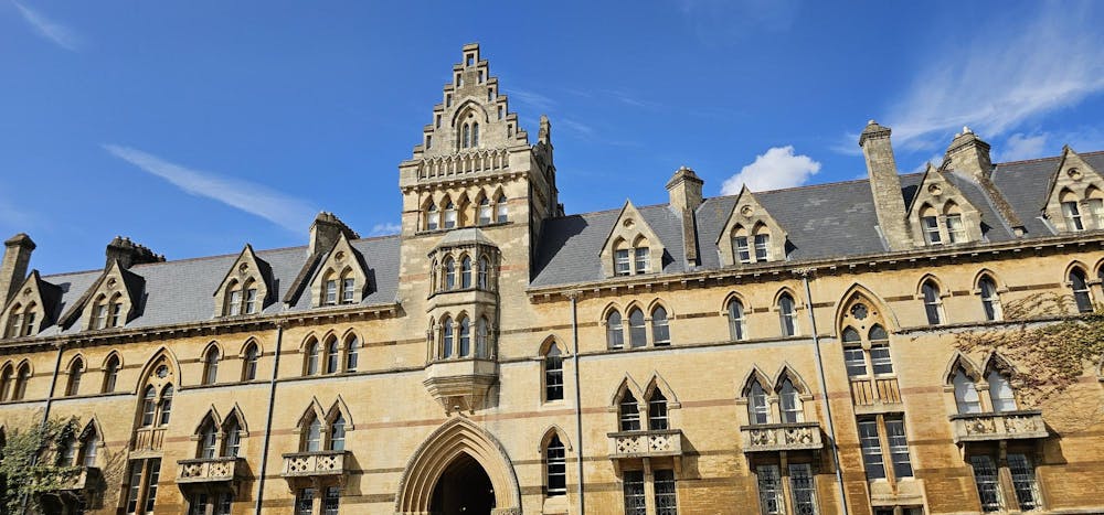 A grand, yellowish, castle-like building with gothic architecture under clear blue skies.