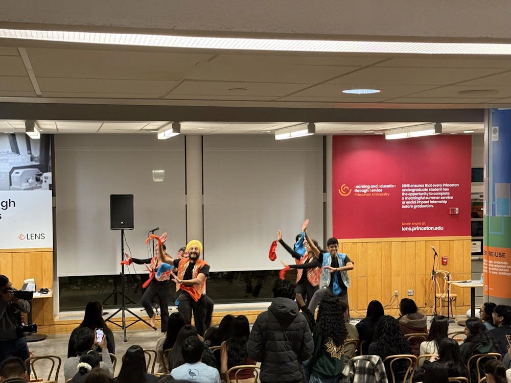 Students perform a dance onstage in front of an audience at a campus event.