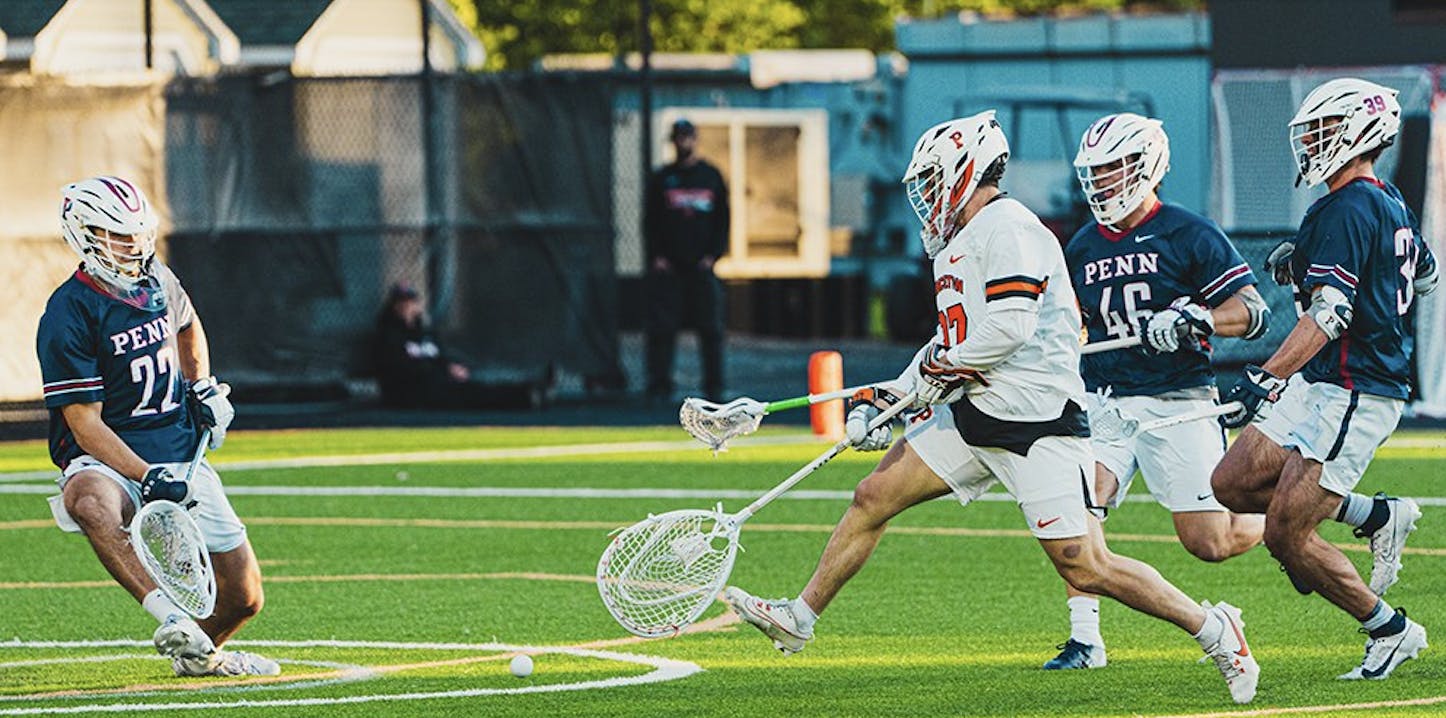 Man in white jersey shoots lacrosse ball.