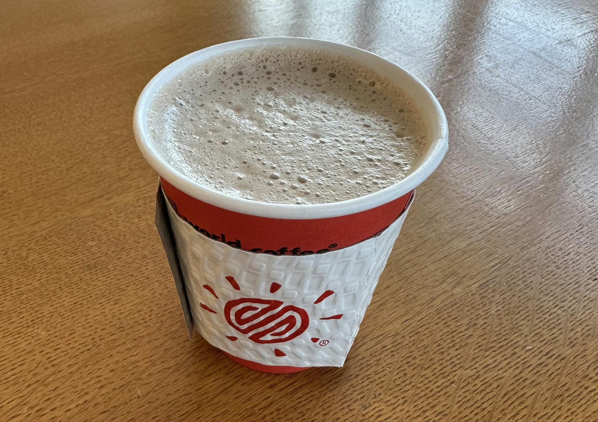 A simple cup of hot chocolate sits on a wooden table.