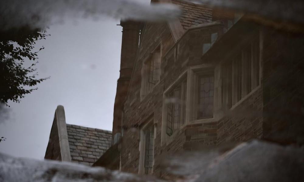 Stone building reflected in a puddle surrounded by dark stone