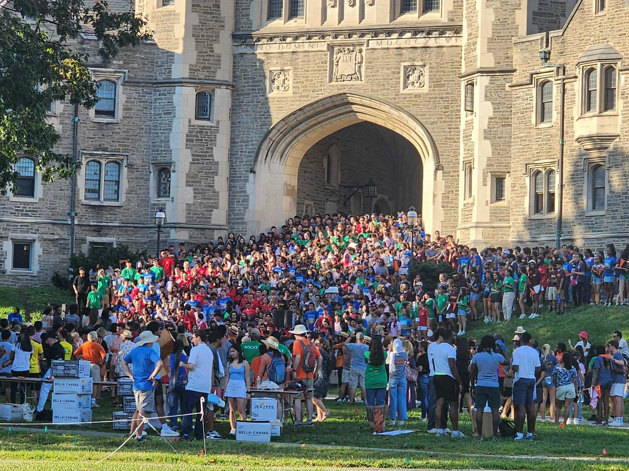 A large group of people wearing colorful shirts poses for a picture on the steps of an arch.