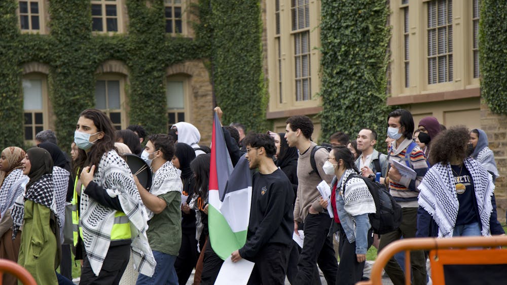 A group of protestors march in front of a building with ivy.