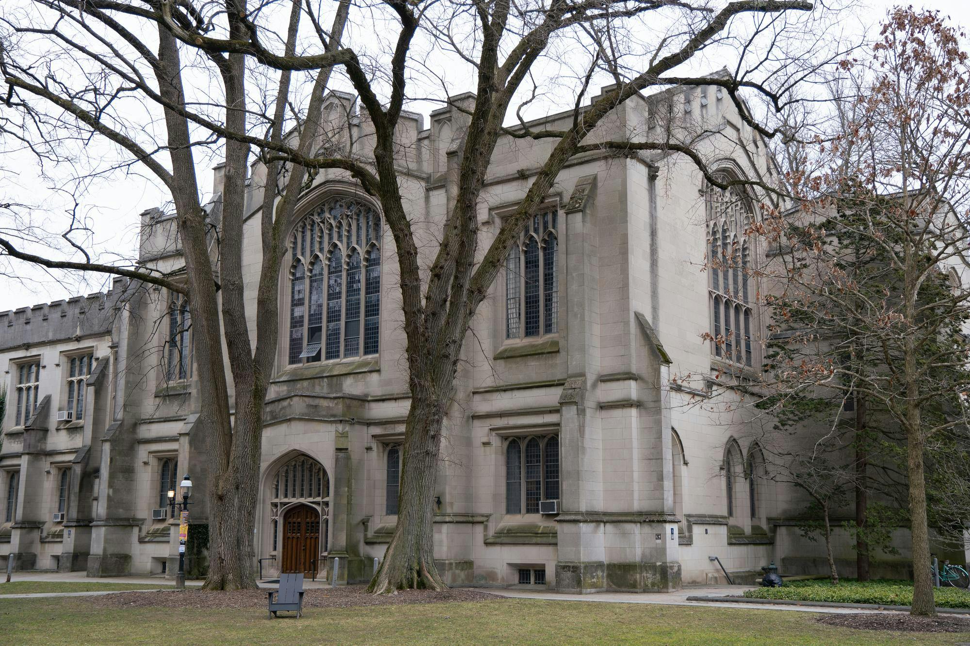 Gothic stone building with large windows and trees in front.