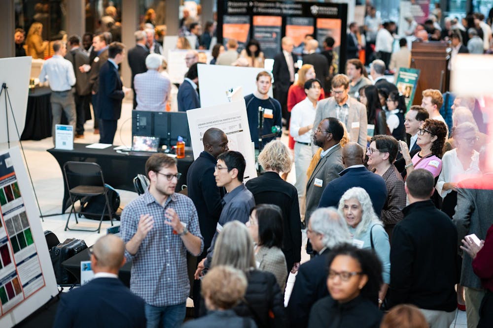 Researchers with posters present their work to a large crowd of people. 