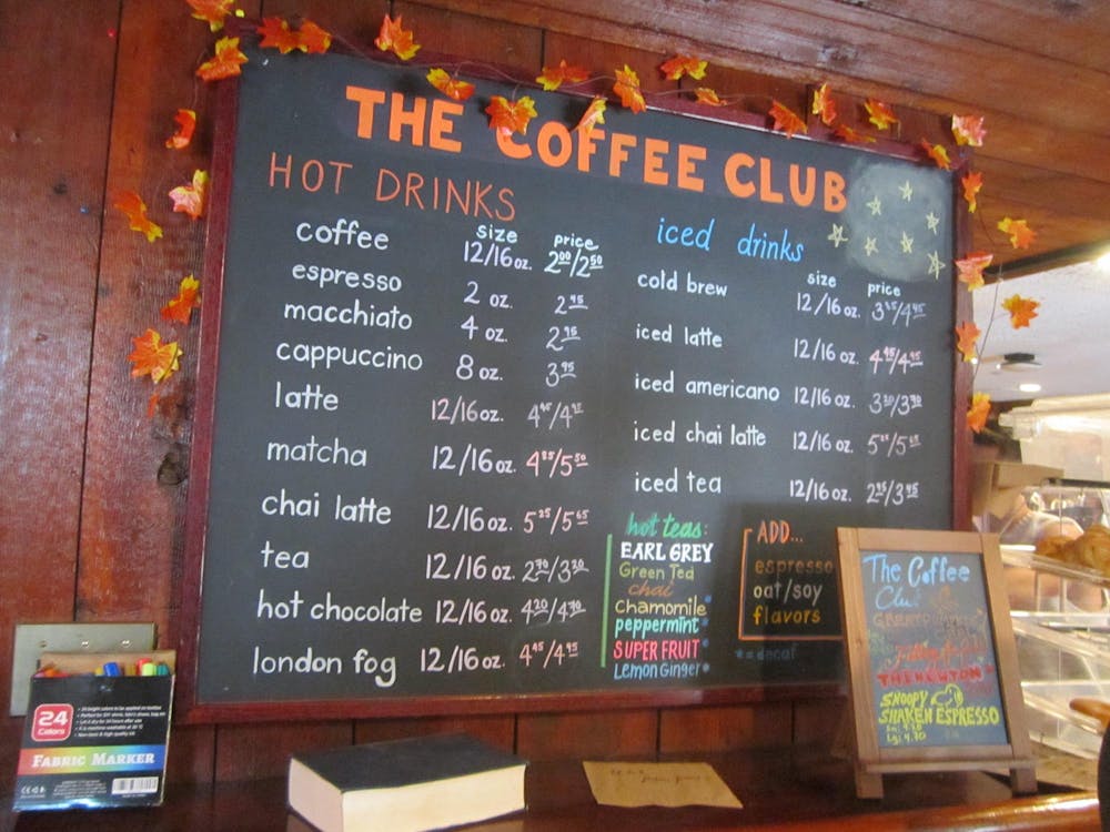 Colorful chalkboard menu with artificial fall leaves scattered around it.