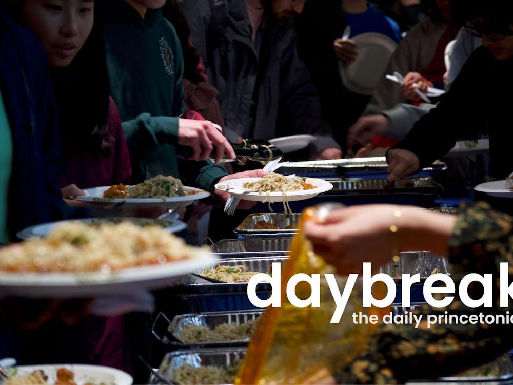 People are taking food from large containers, placing them on plates with tongs. In the foreground, text reads "Daybreak: Daily Princetonian."