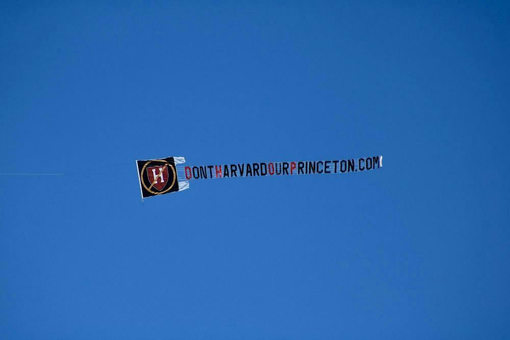 A photograph of the sky with a flying banner reading, “DontHarvardOurPrinceton.com”
