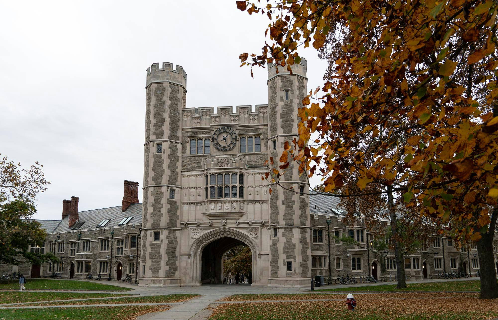 Tall Gothic Arch with two medieval watchtowers and a clock. Cloudy day with fall leaves in the front.