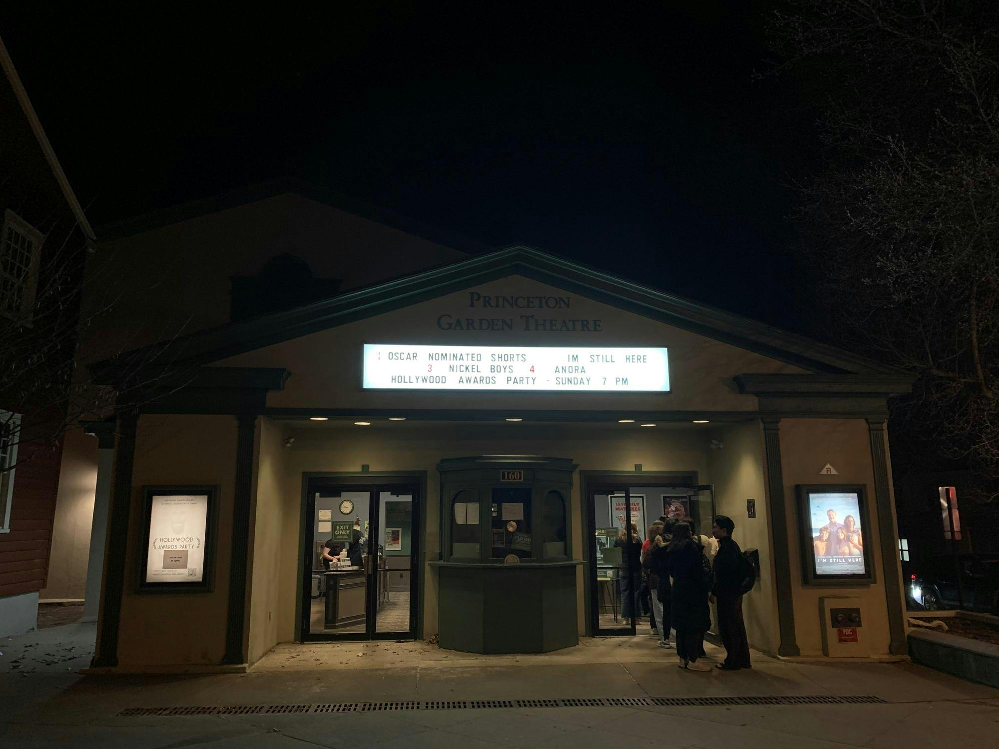 Sign outside of Garden Theatre announcing movie, with students in line for movie. 