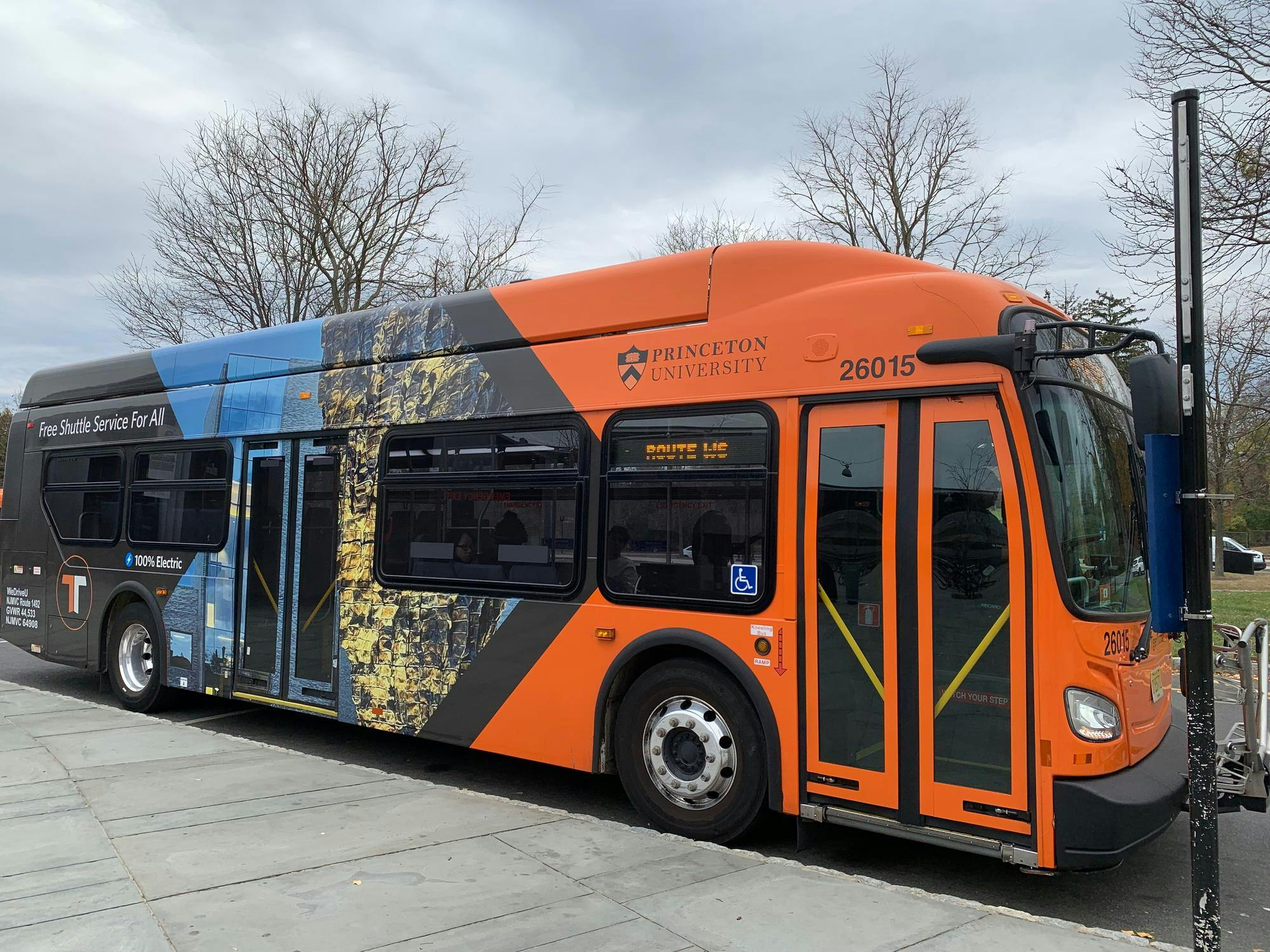 An orange and black bus is parked against a curb.